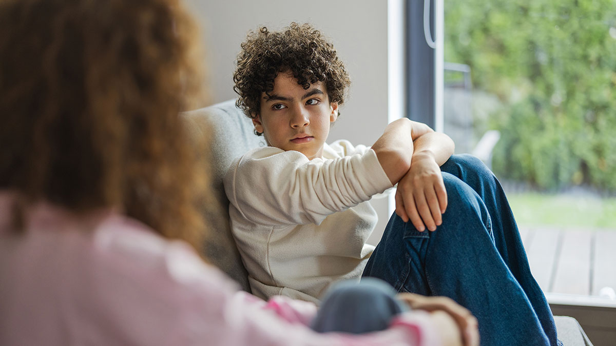 Son sitting on couch looking at his mother Son sitting on couch staring at his mother.