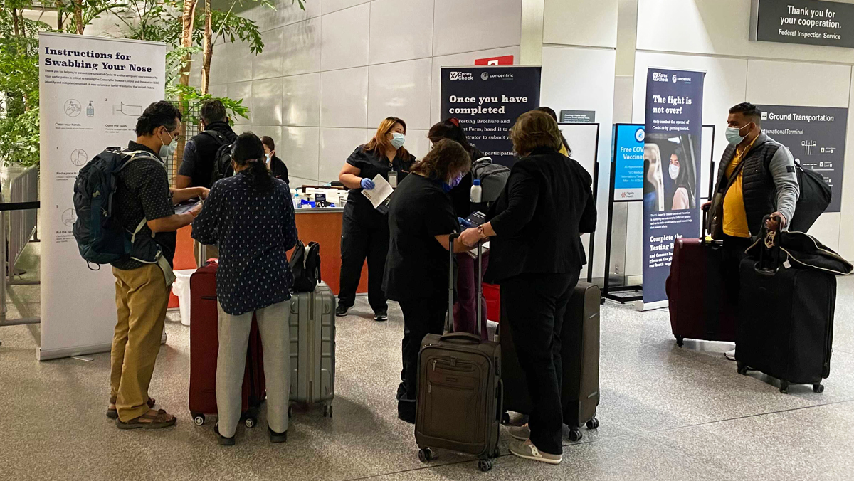 Travel-surveillance Travelers gather at a testing station in the San Francisco International Airport