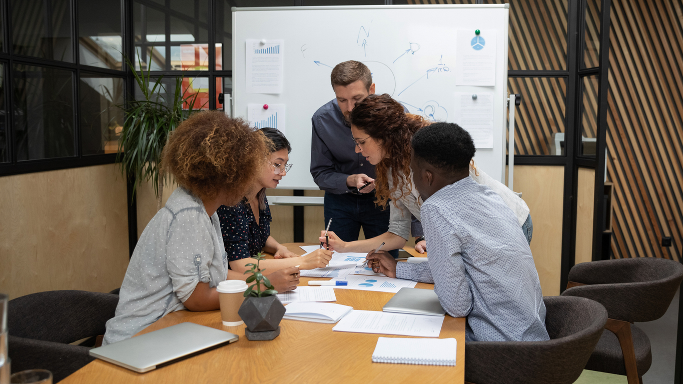 AlcoholGroupAnalyzingDataStats1181590479.jpg Five people are collaboratively working on a data report that is spread across the table.