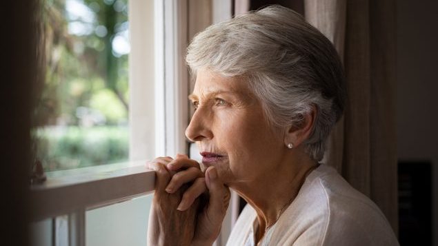 Woman looking out window Older woman looking out a window
