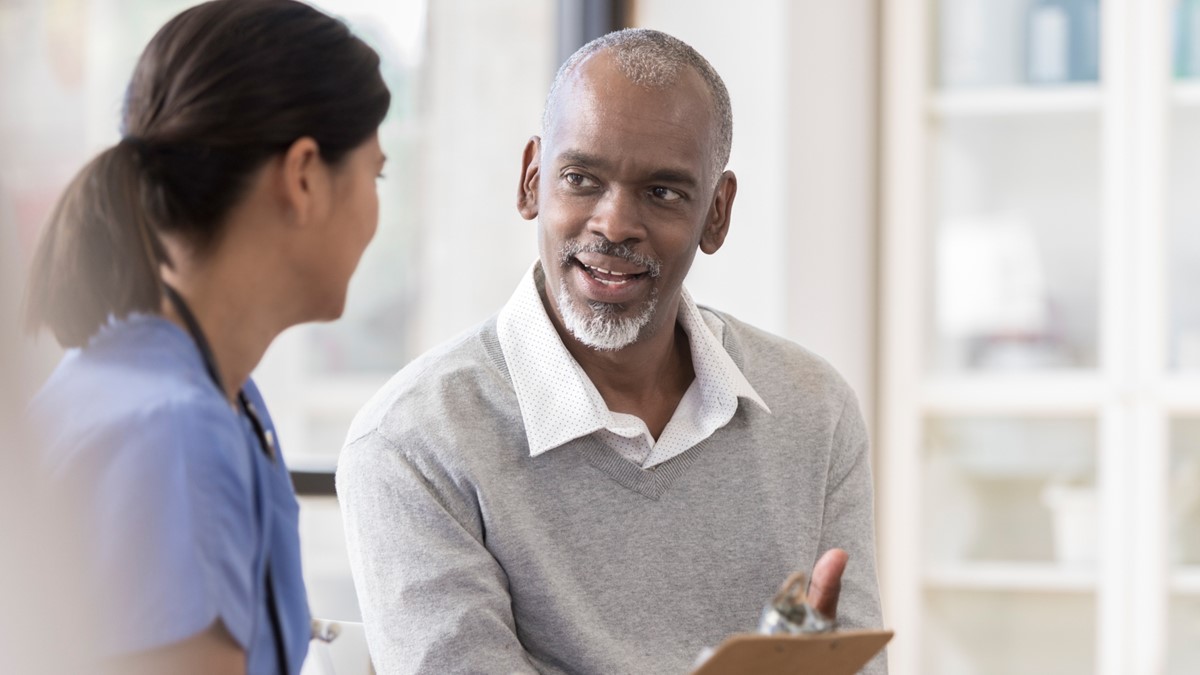 HCP and smiling patient A healthcare provider talks to a smiling patient in an office.
