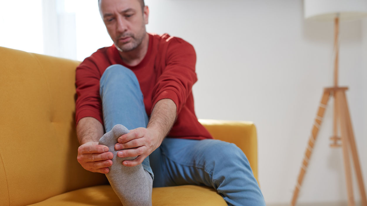 Man with foot pain at home Man holding his toe in pain.