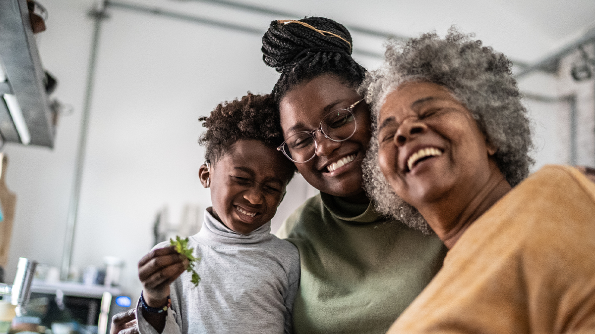 A young boy is smiling with his mother and grandmother.