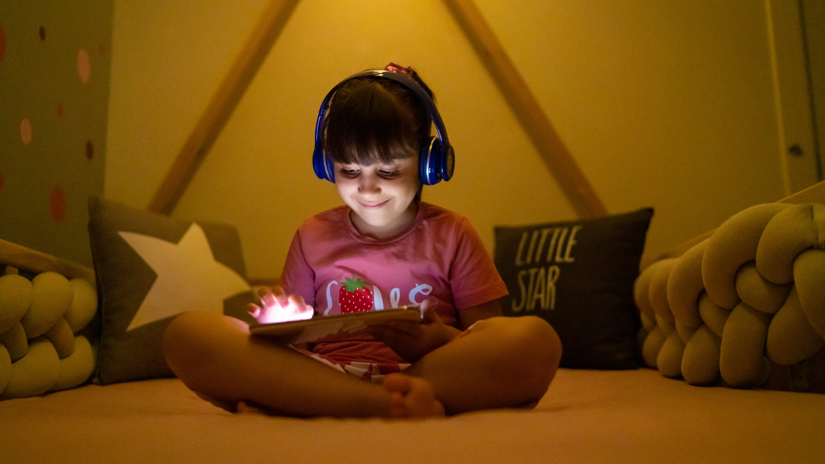 Kid reading on iPad while on bed.