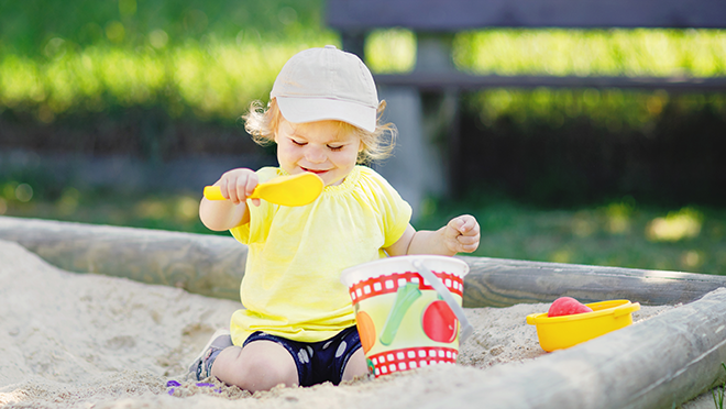 child sandbox Child playing in sandbox with bucket and shovel,