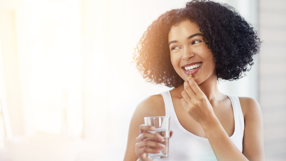 — title missing — Young woman smiles taking a vitamin.