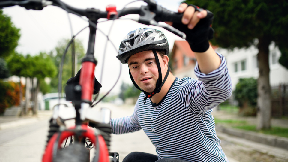 — title missing — Teen with Down syndrome looking at their bike.