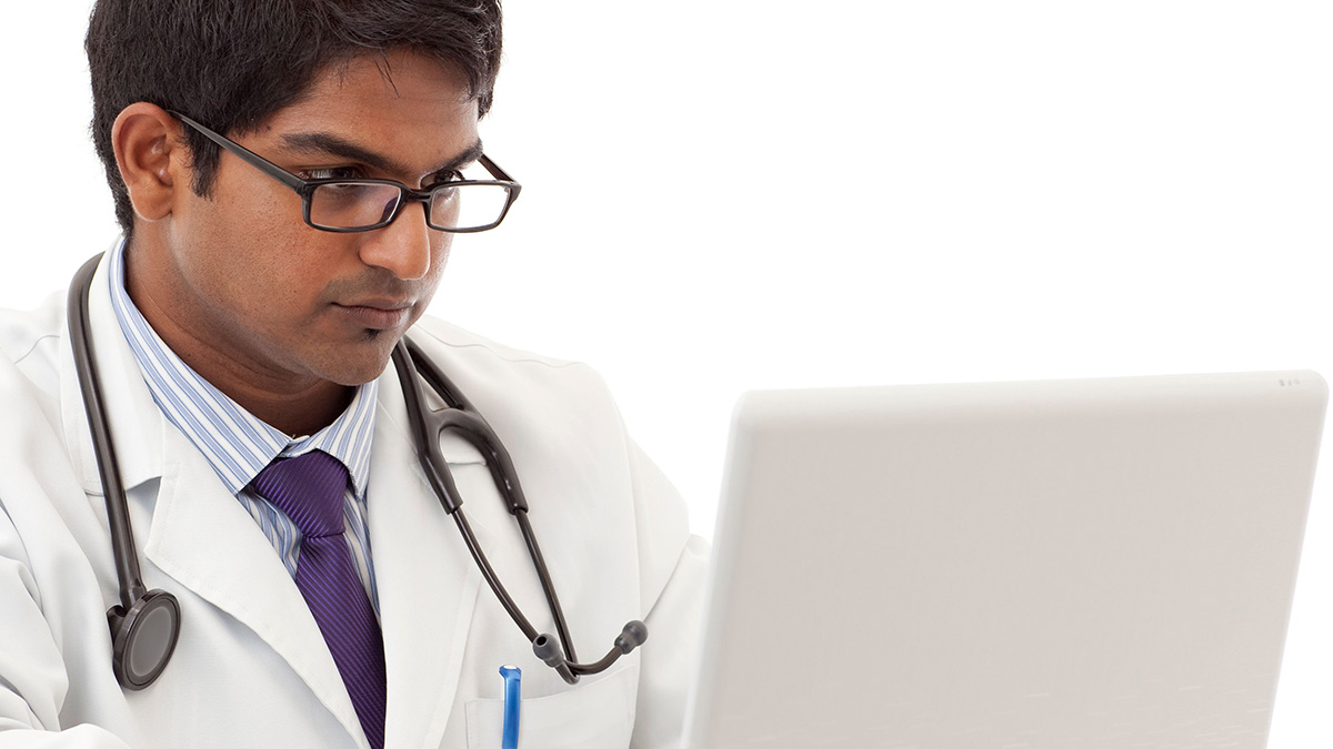 Doctor on a laptop Male healthcare provider with serious face working on laptop