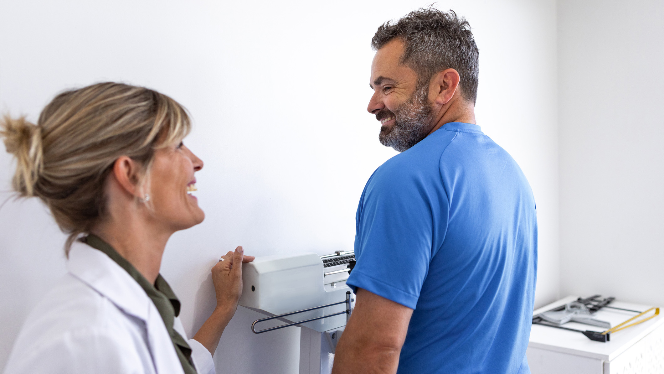 Man getting weighed A man stands on a scale with a health care provider looking on.