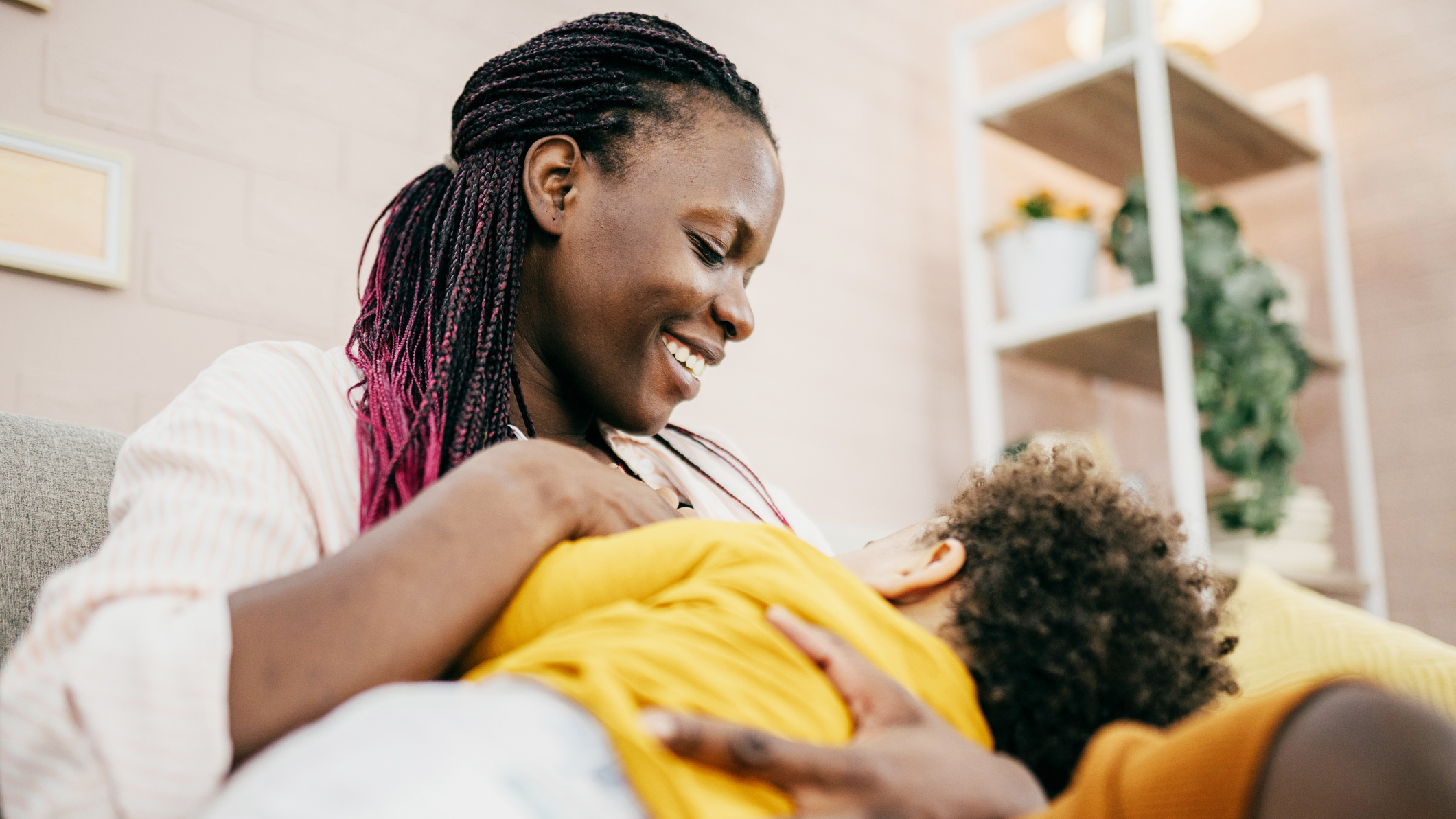 Breastfeeding Report Card - Breastfeeding Mom A mom smiles at her young child whom she cradles as the child breastfeeds.
