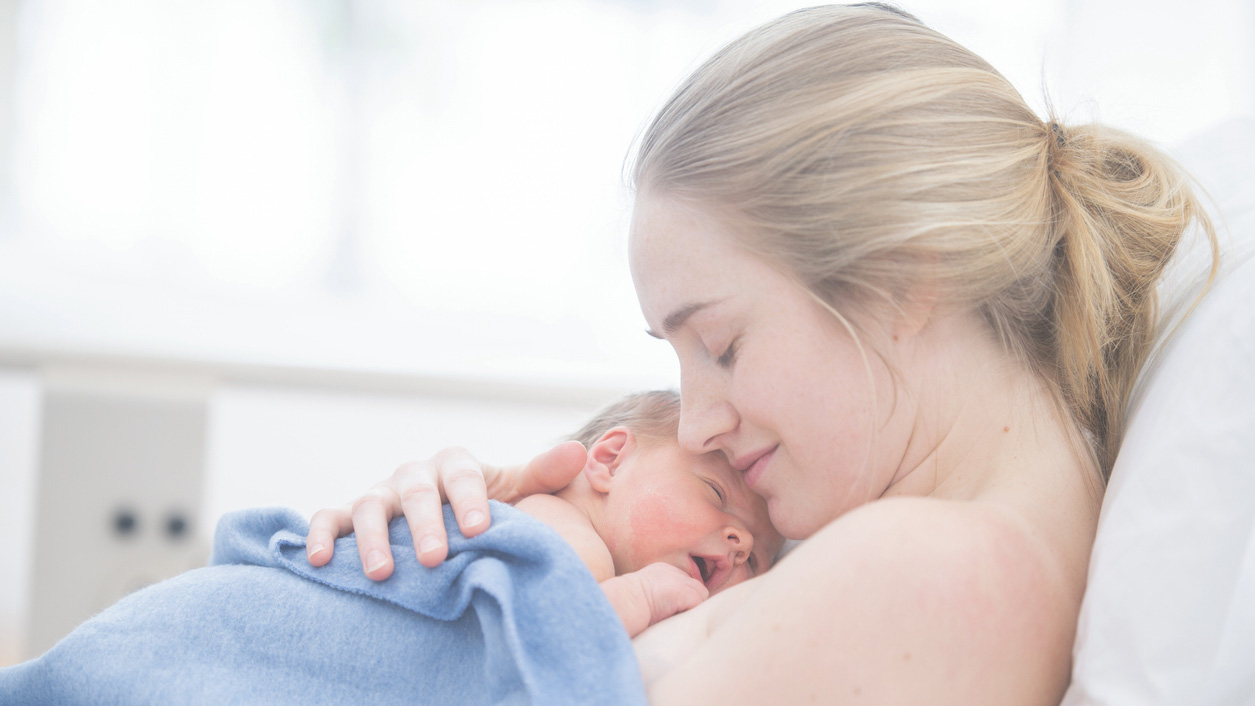 mPINC survey methods A mother is cradling her newborn baby. They are indoors in a hospital room.