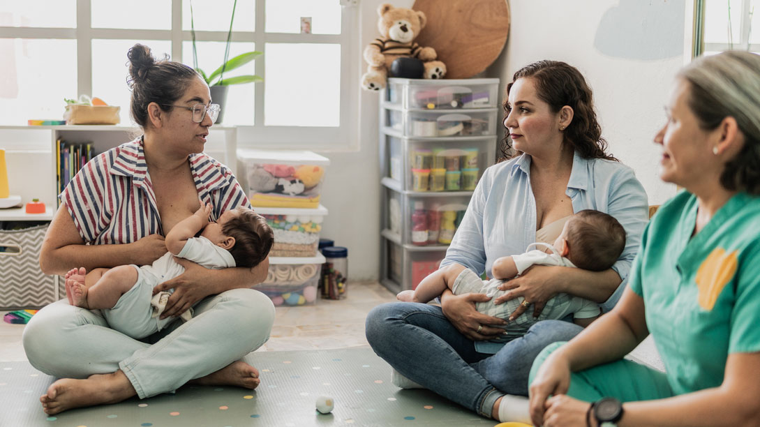Mothers breastfeeding their babies A group of moms sit on the floor and breastfeed their babies.