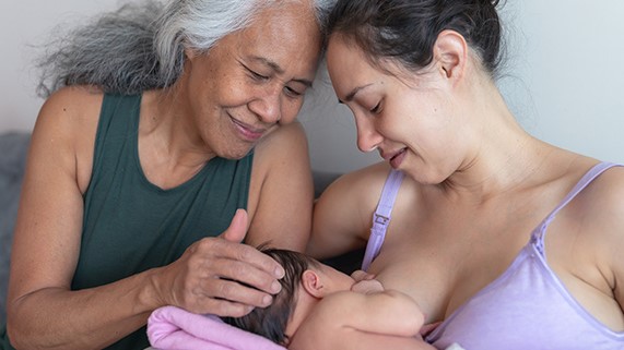 — title missing — A woman breastfeeding a child while a grandmother offers support.