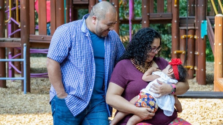 -- title missing -- Parents with child at a park while mother is breastfeeding.