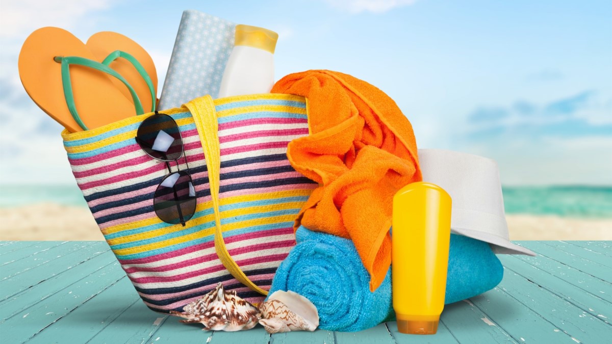 Beach Bag a colorful tote bag containing sunscreen, sunglasses, a hat, towels, and shoes