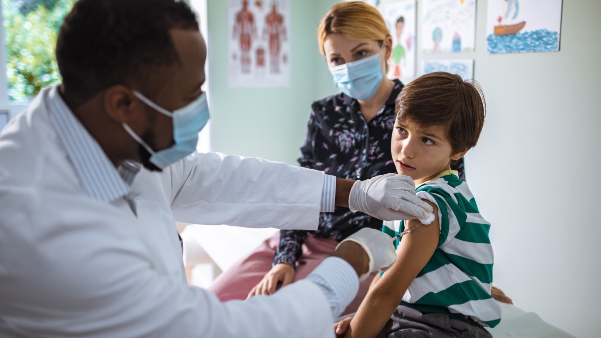 Boy Vaccine a doctor giving an HPV vaccine to a boy while his mother looks on
