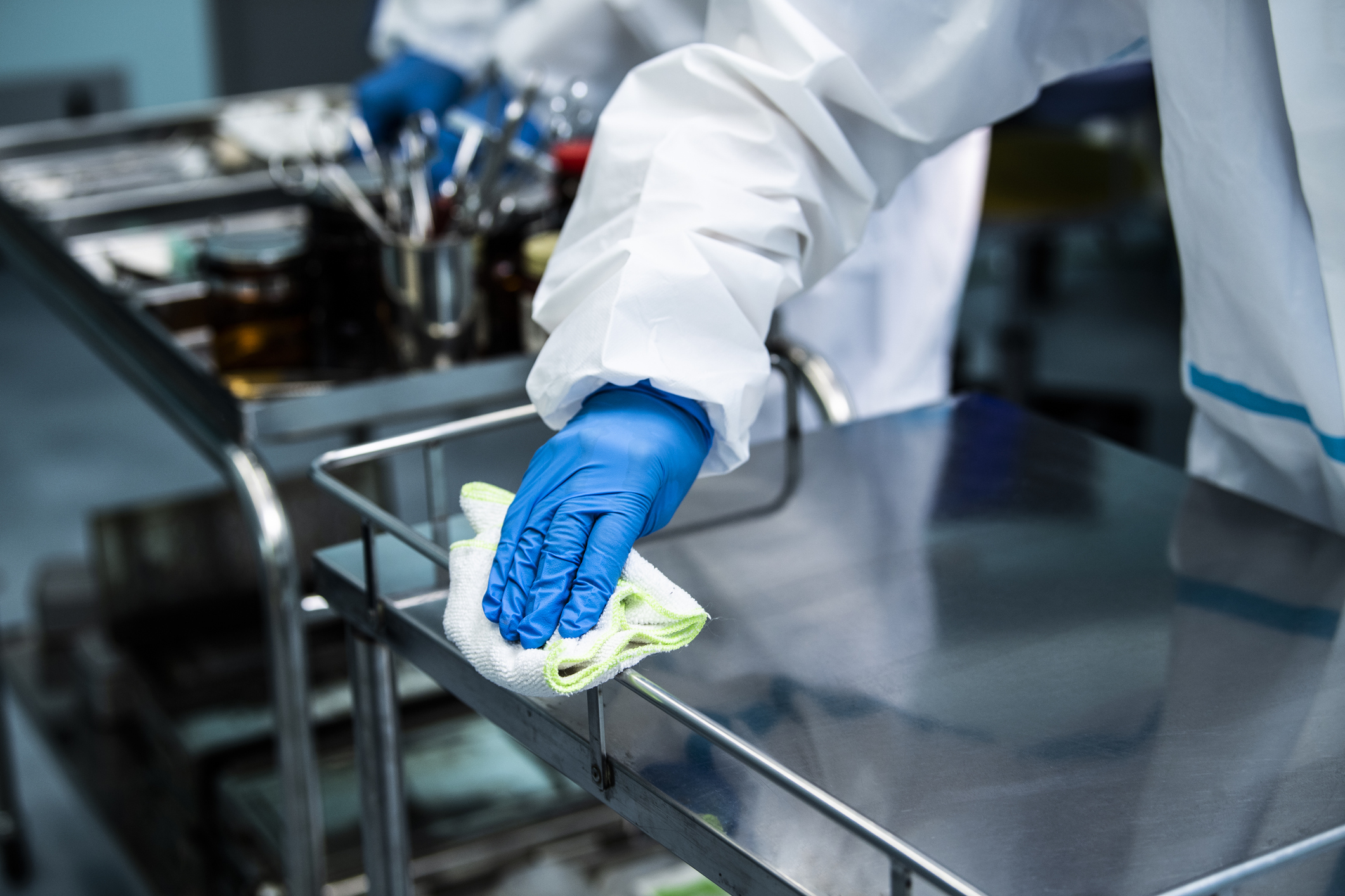 Hospital worker cleaning a cart.