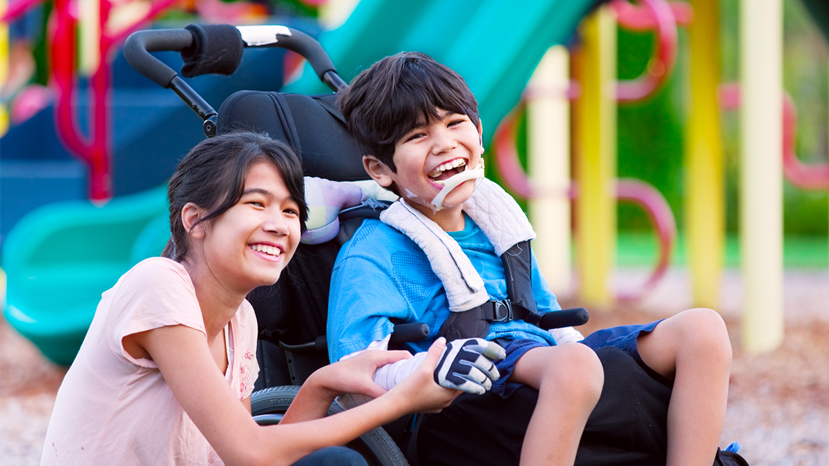 Boy with cerebral palsy sitting next to his sister Boy with cerebral palsy sitting next to his sister
