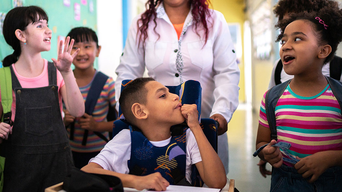 — title missing — Teacher and students walking in the corridor at school, including a student with a disability