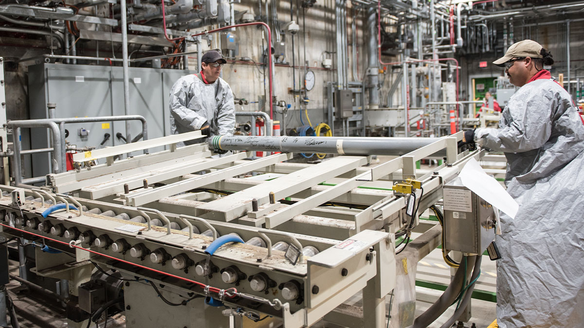Last rocket at BGCAPP An image of two worker in personal protective equipment loading a chemical munition onto a conveyor.