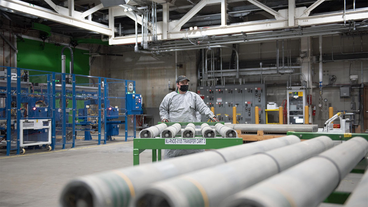 Processing Rockets at BGCAPP An image of a worker in personal protective equipment loading chemical munitions onto a conveyor.