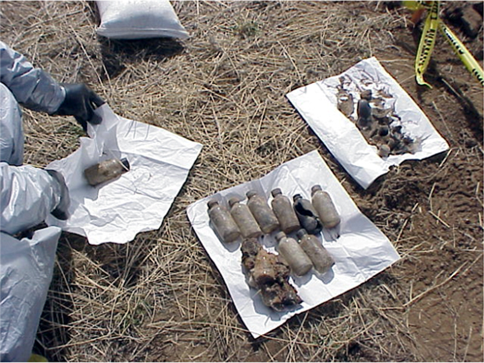 Worker handling CAIS An image of workers examining recovered chemical agent materials.