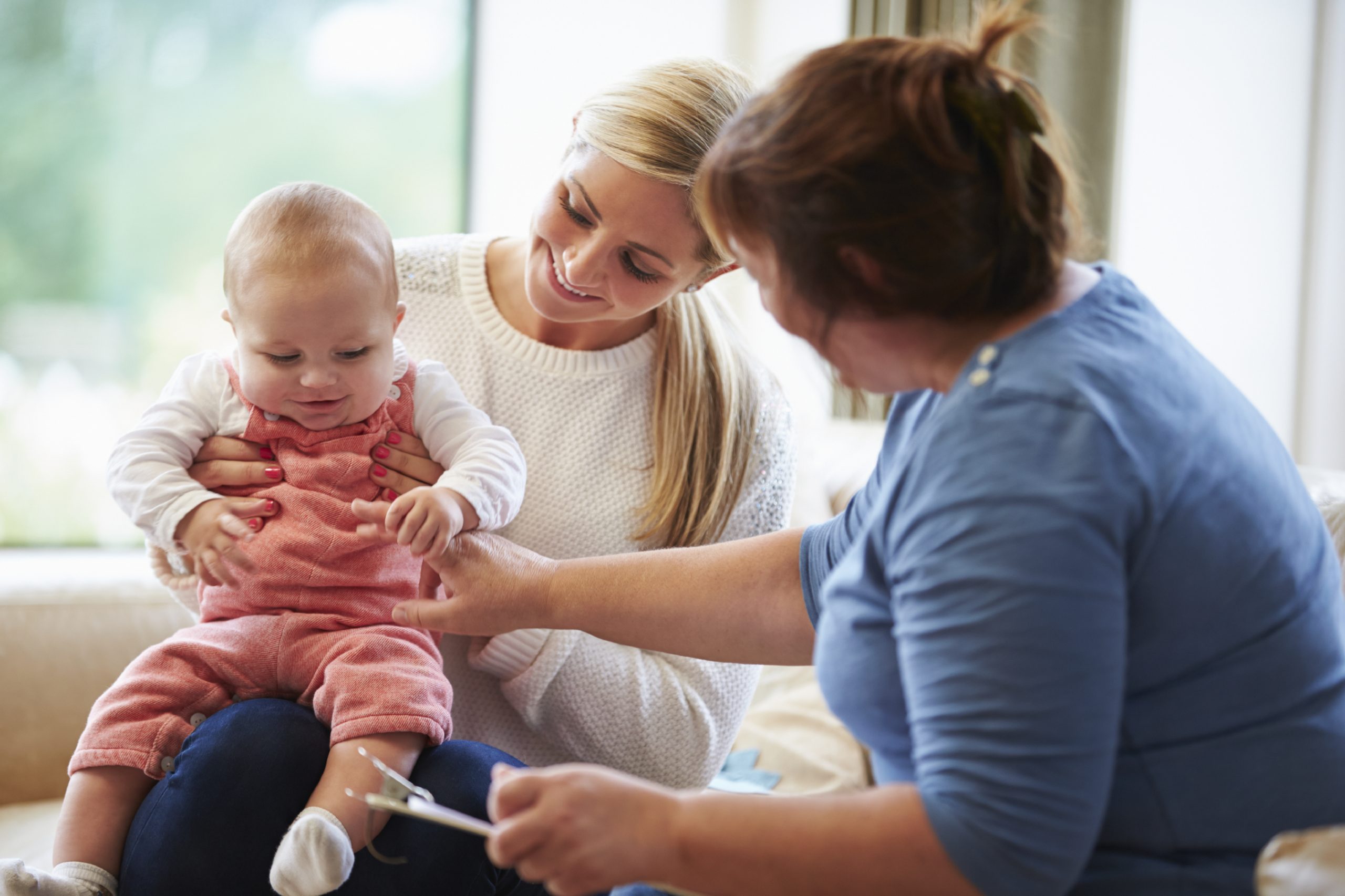 Mother and baby with a home visitor Health visitor talking to a mother with young baby