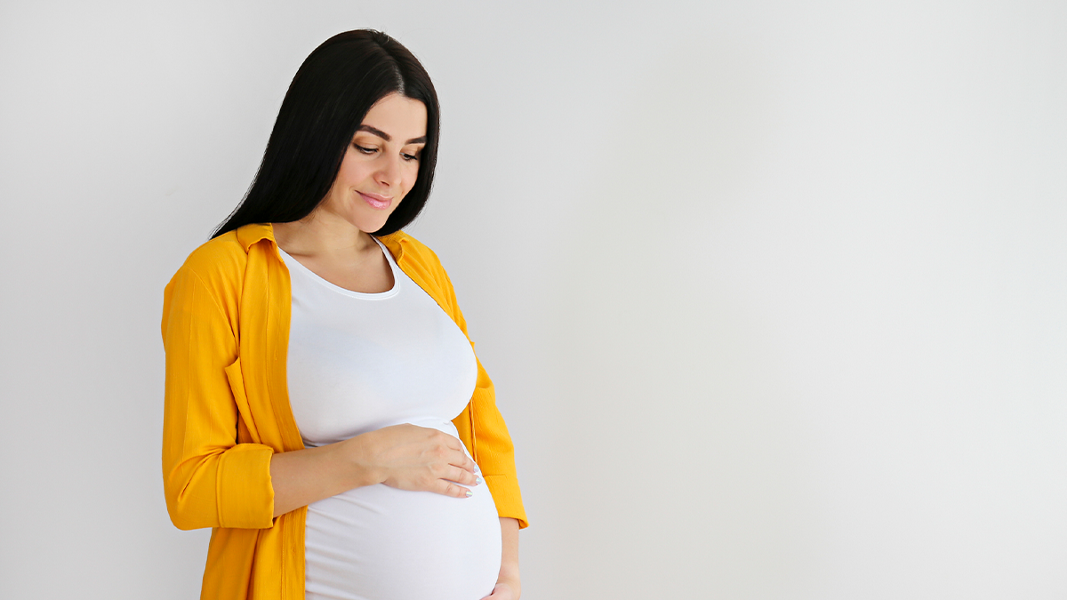 Pregnant woman with yellow shirt holding belly Pregnant woman with yellow shirt holding belly
