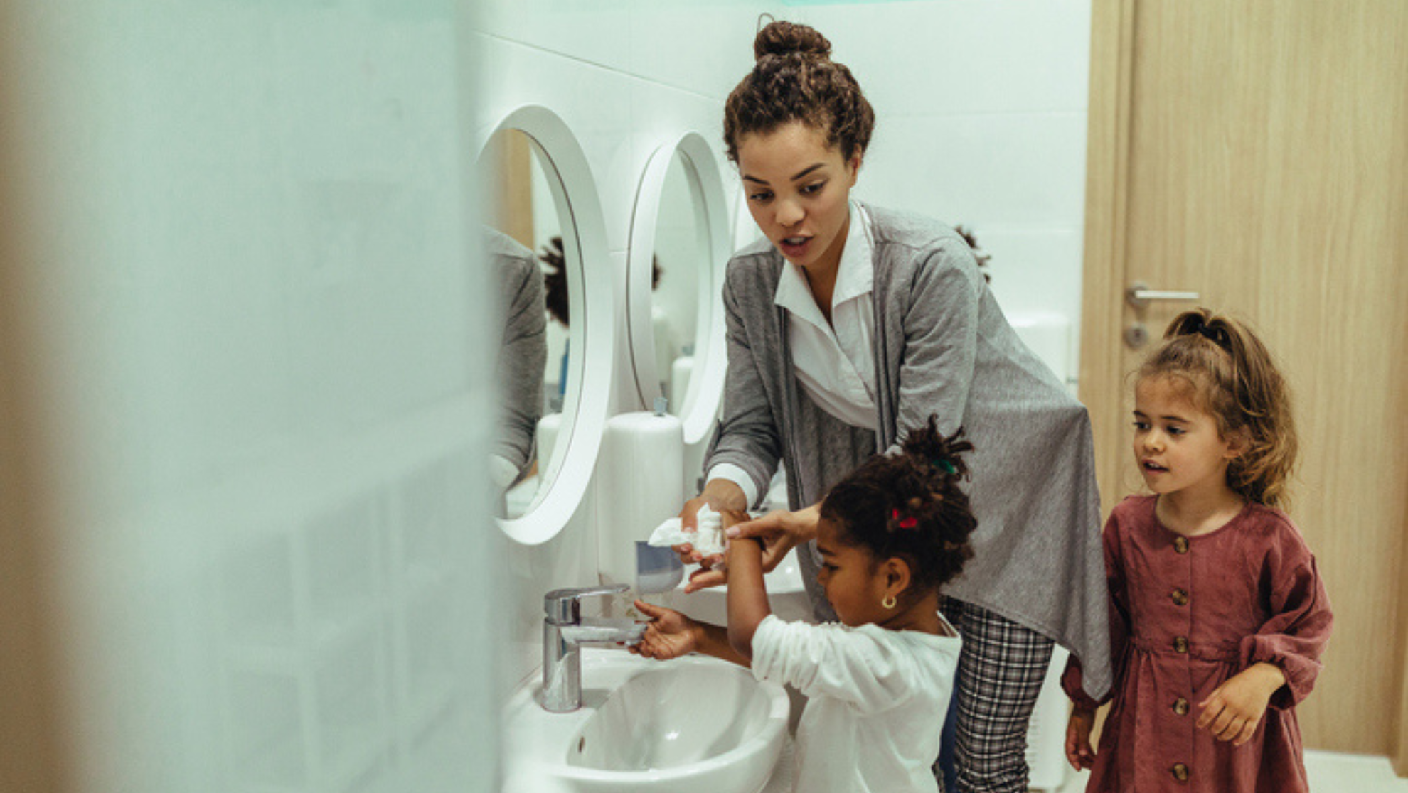 teacher helping child wash their hands teacher helping child wash their hands