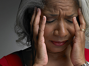 image.png A mature woman with her head in her hands and eyes closed.