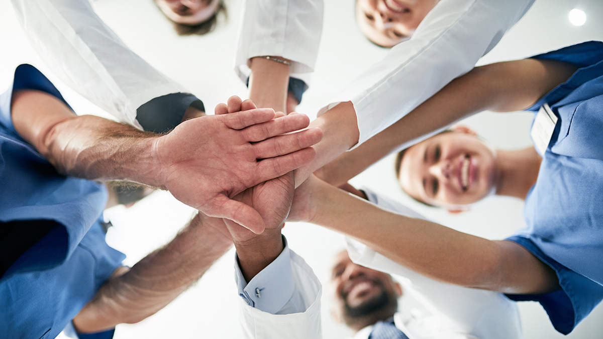 Stroke systems of care A group of medical professionals standing in a circle and joining their hands together in the middle