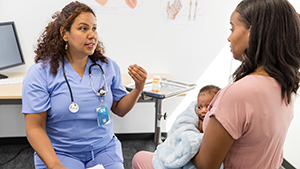 HCP and parent healthcare provider talking to mother who is holding infant in a doctor's office exam room