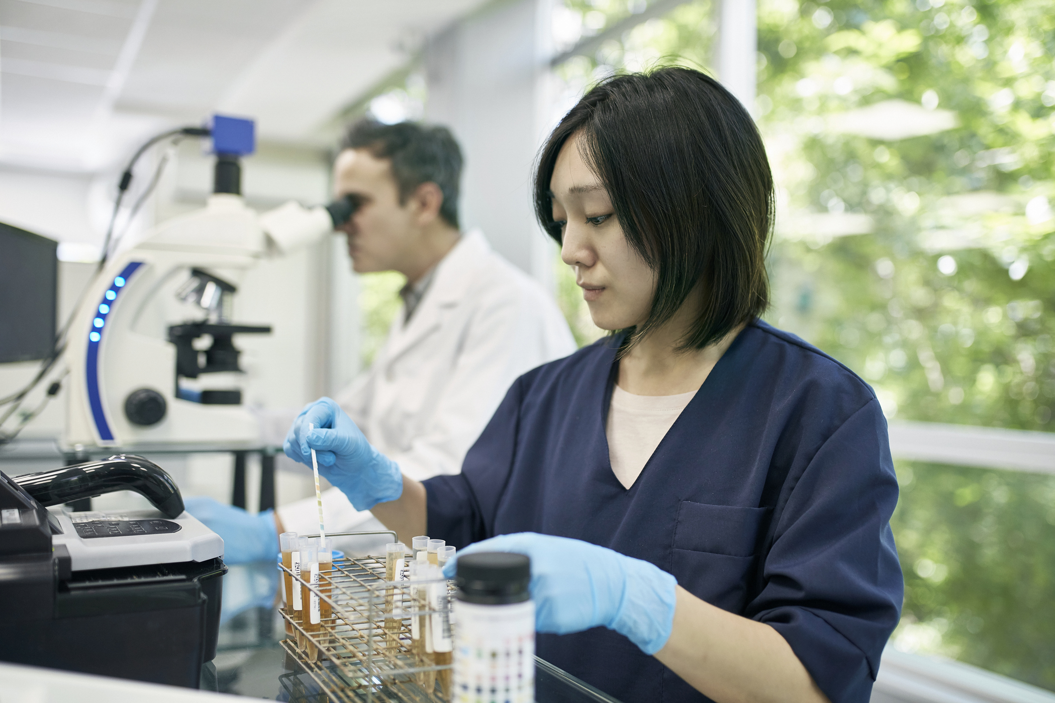 A laboratory worker performing analysis on samples in test tubes.