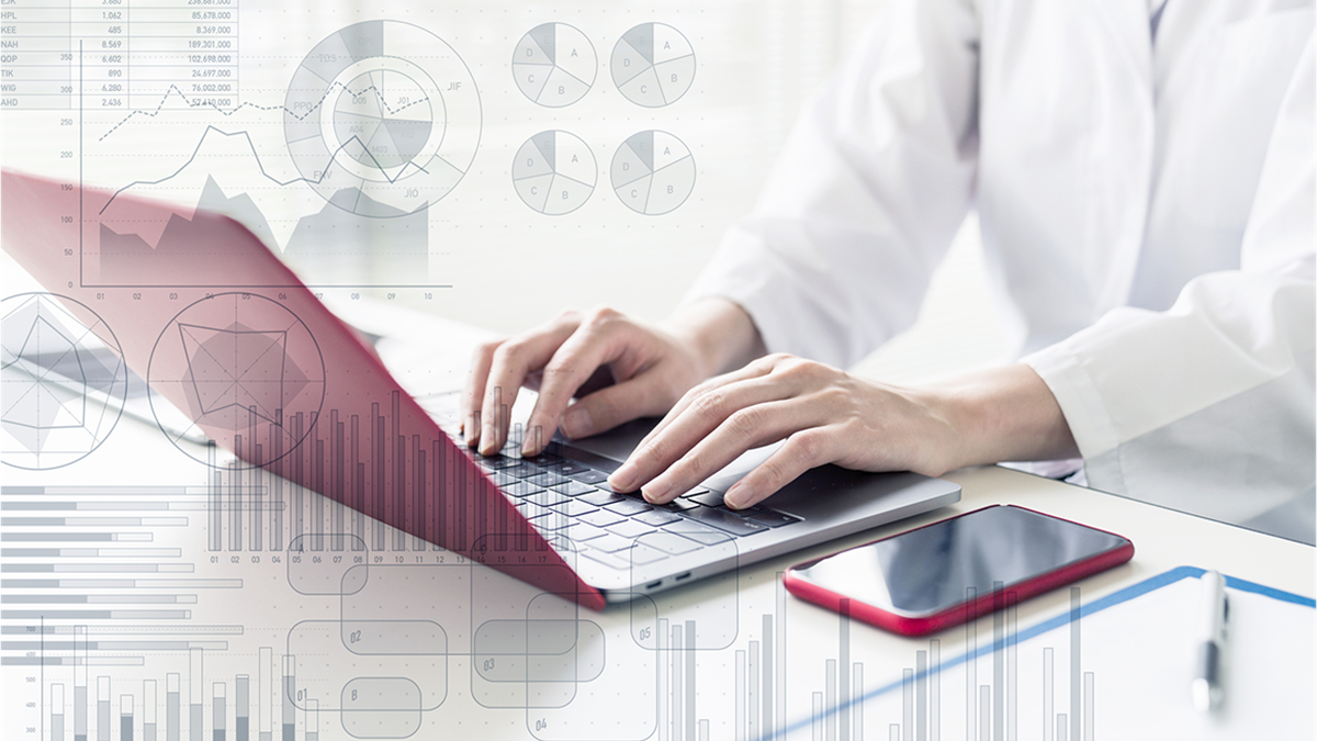 Photo showing a person typing on a computer with translucent data visualizations superimposed.