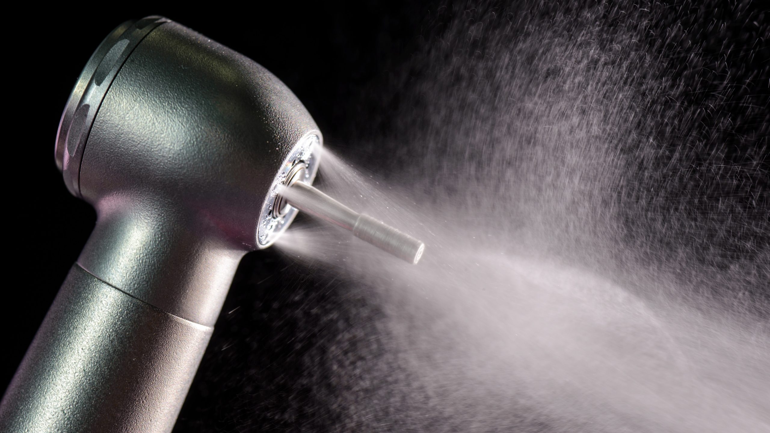 DUWQ Thumbnail Black background with a silver dental handpiece spraying water.