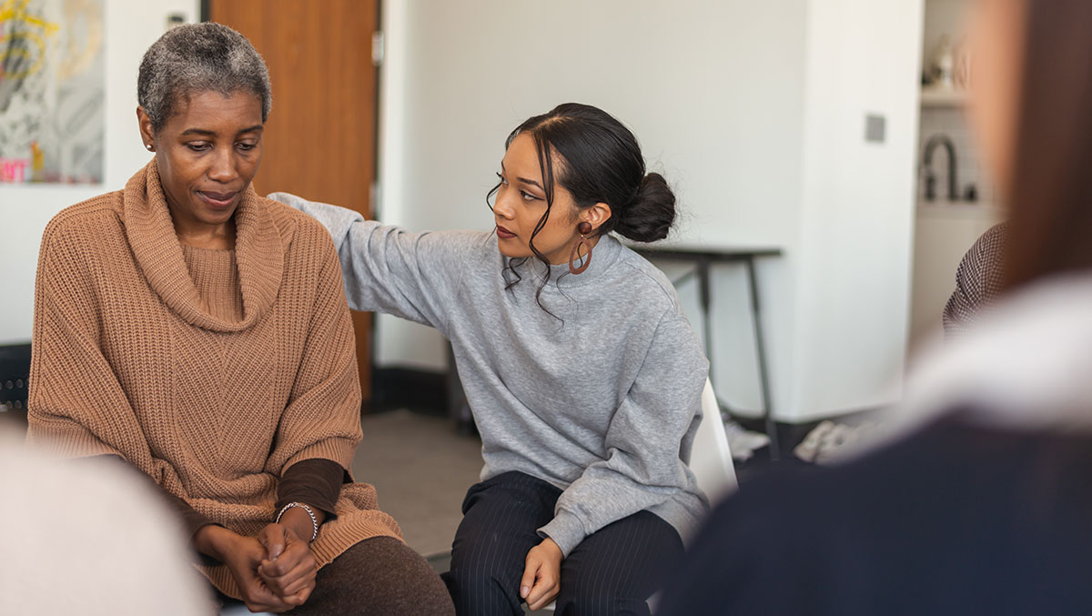 Young woman shows support in therapy session Mujer dando apoyo a otra mujer en una sesión de terapia.