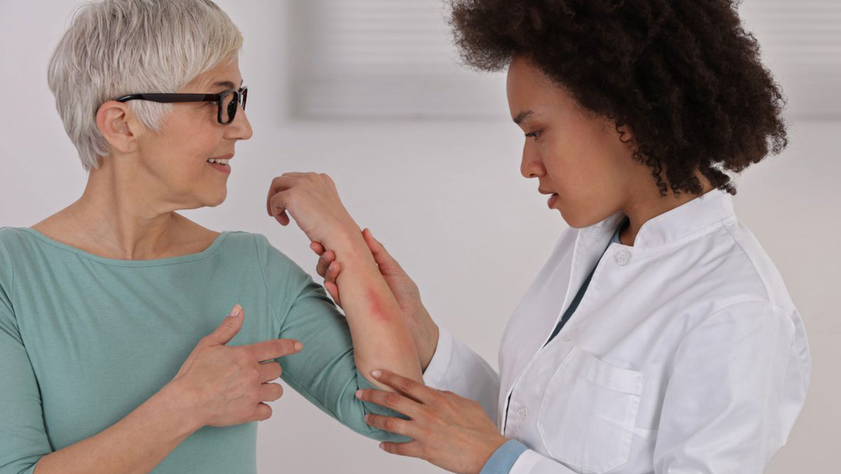 Doctor dermatology and patient Una mujer mayor con un sarpullido en el brazo es examinada por una dermatóloga.