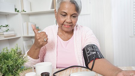 — title missing — Older woman sitting and checking her blood pressure.