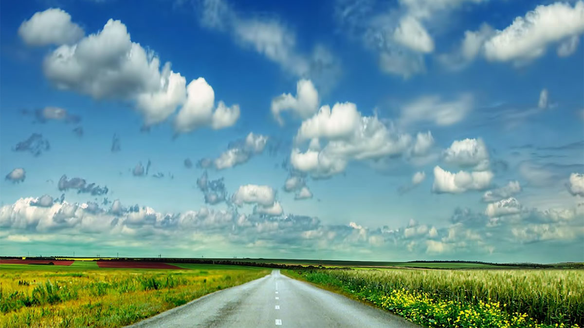 — title missing — A highway stretching off to the horizon on a sunny day with puffy clouds