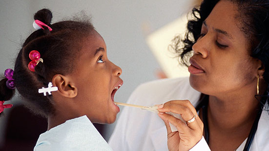 Doctor young girl Image of a doctor examining the throat of a young child with a tongue depressor.