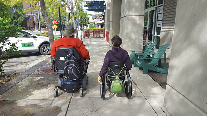 Man on scooter with woman in wheelchair Man on scooter with woman in wheelchair