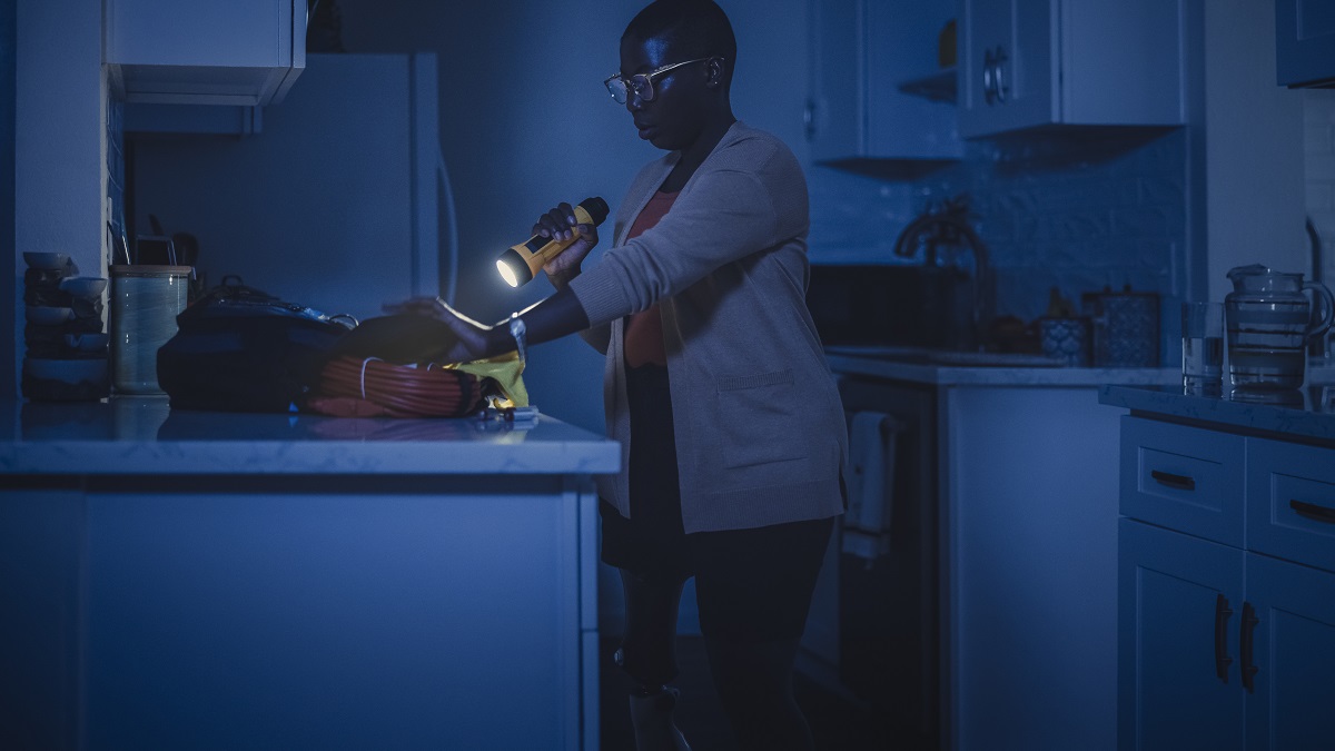 Woman with flashlight Person with a prosthetic leg in a dark kitchen holding a flashlight, standing by the counter.