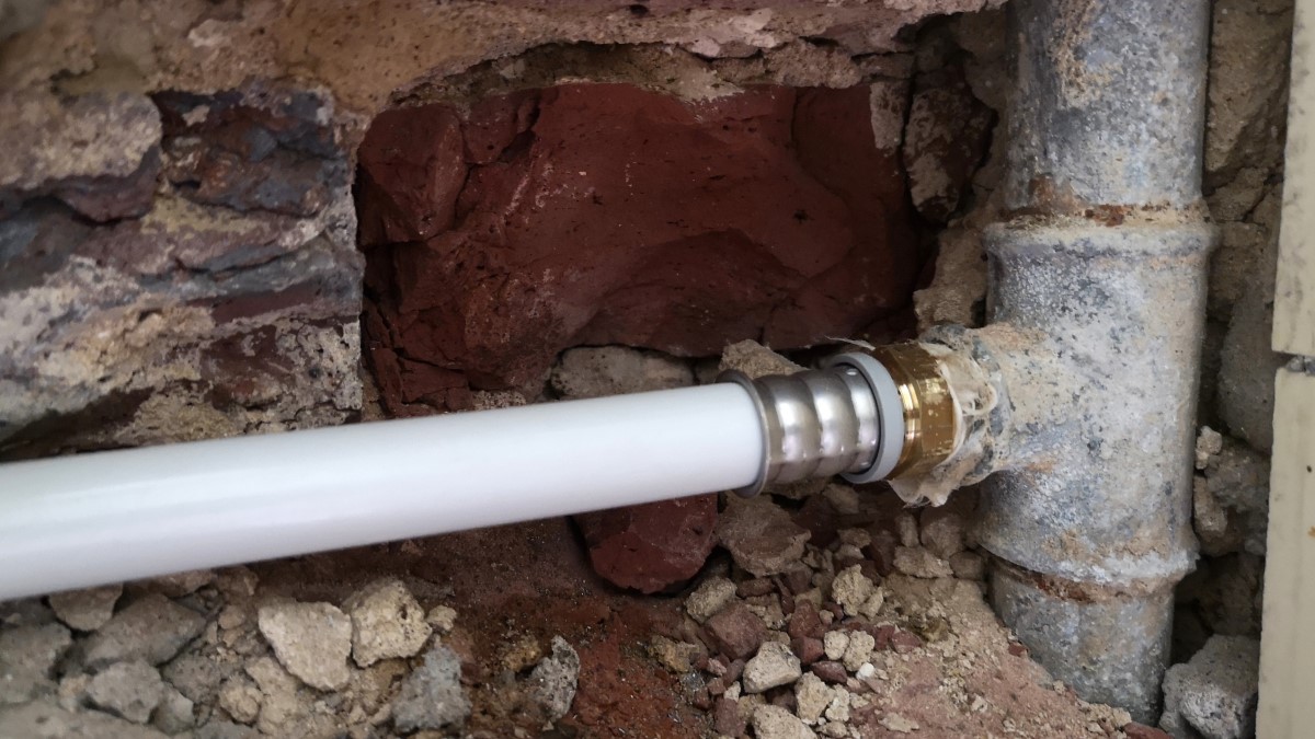 Water pipe Old metal water pipe in the wall connected to a plastic pipe