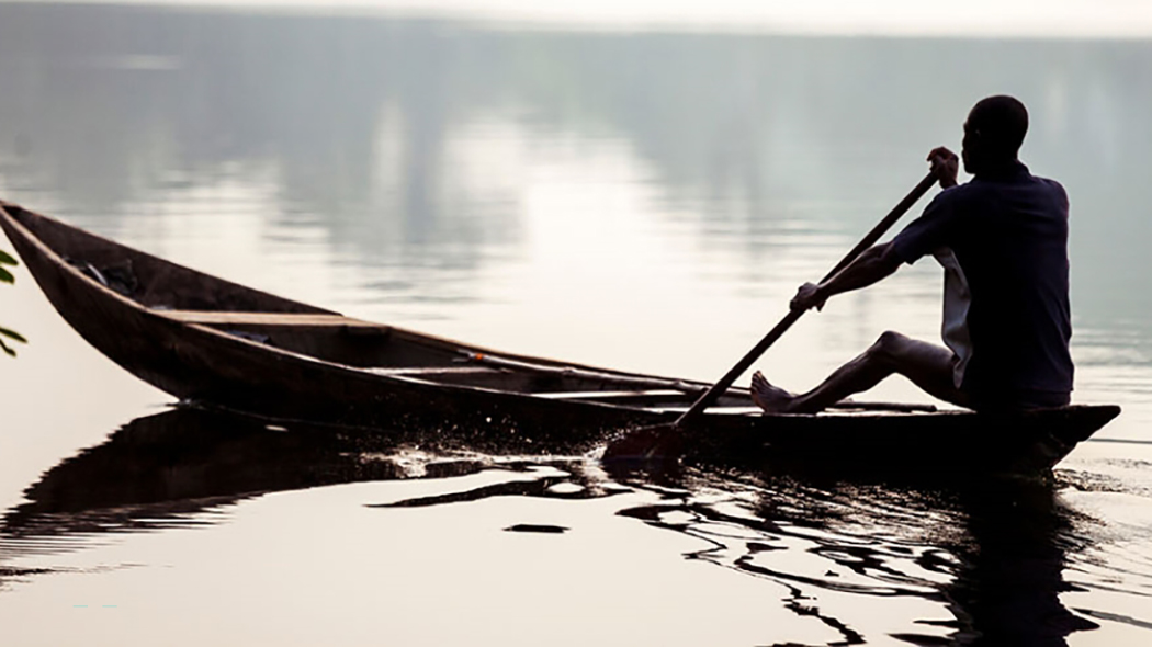 Man in canoe African man rowing a boat on a lake