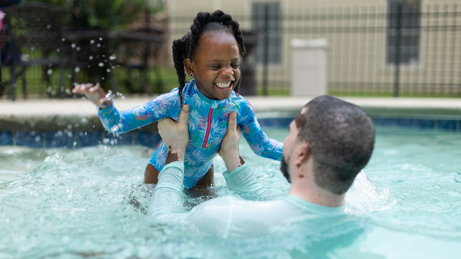 DP223PoolPlayBlackGirlDad.jpg Father and daughter play in swimming pool.