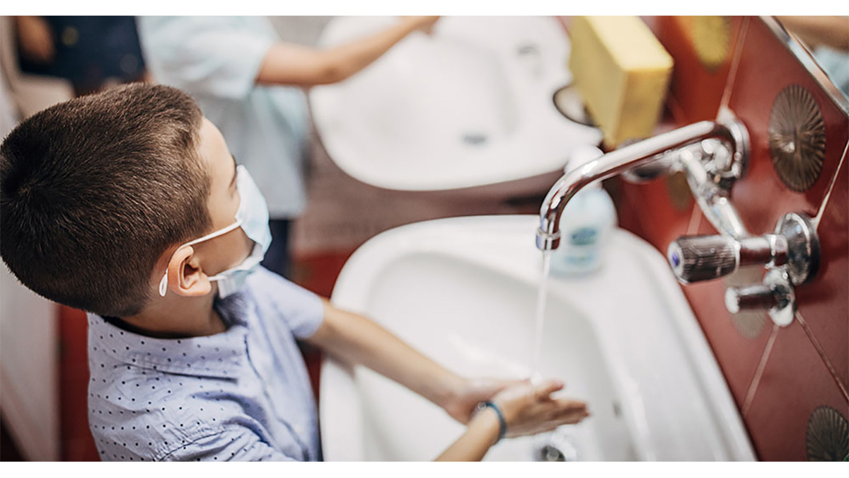 Boy wearing mask washing hands Young boy wearing a mask while washing his hands in the bathroom sink