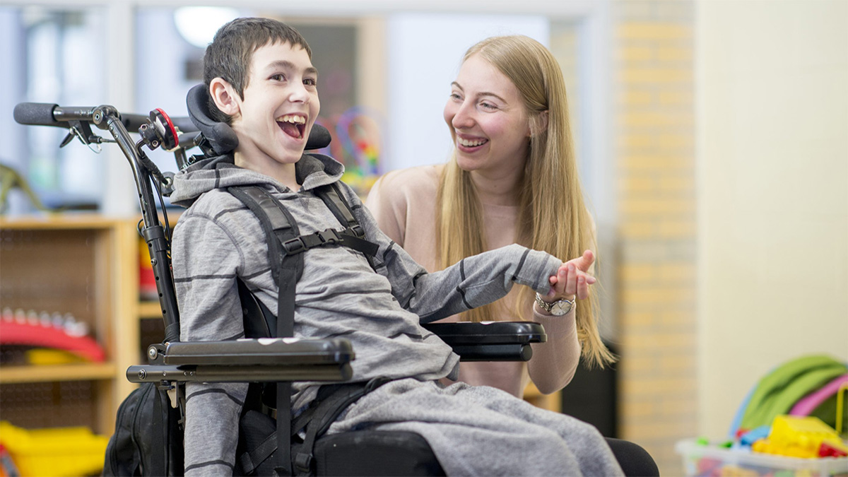 Caregiver sitting alongside student Caregiver sitting alongside student with a mobility disability.