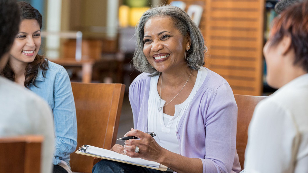 Senior female mental health professional facilitates group therapy session Three women sitting in a circle talking with each other