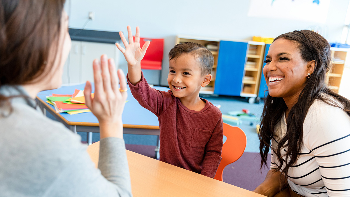 Preschool teacher and boy A mother and her son smile during a meeting with an early care and education provider.