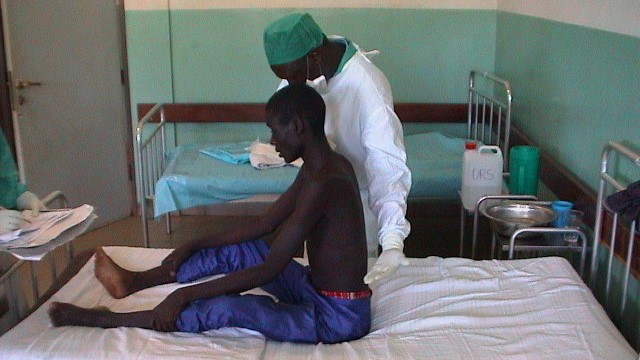 Ebola survivor exam A healthcare provider examines a male Ebola survivor who is sitting on a hospital bed.